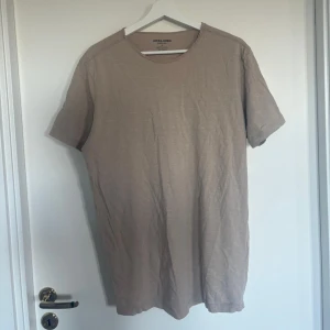 Beige t-shirt från Jack and Jones - Enkel och stilren beige t-shirt från Jack and Jones med rund halsringning och normal passform. Perfekt basplagg till garderoben. T-shirten är kortärmad och gjord i mjukt bomullsmaterial.