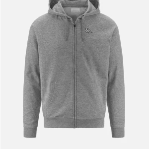 Grå hoodie med dragkedja från Kappa - Säljer en stilren grå hoodie från Kappa med dragkedja framtill och huva med dragsko. Tröjan har två fickor och en liten Kappa-logga på bröstet. Perfekt för en avslappnad look.