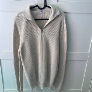 Beige stickad quart zip tröja från Zara - Säljer en beige stickad tröja från Zara med halv dragkedja och hög krage. Bara använd vid fåtal tillfällen.