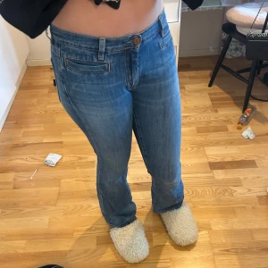 Blå bootcut jeans med broderad detalj - Säljer ett par lågmidjade blå jeans med bootcut passform. Jeansen är i storlek 28 från MiH JEANS från 2000-talet.