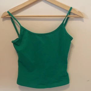 Grön linnetopp - Säljer en enkel grön linnetopp med smala axelband. Perfekt att matcha med jeans eller kjol för en fräsch look. Toppen har en rak passform och är tillverkad i mjukt material.