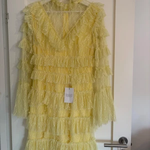 Gul volangklänning Rosa dress från By Malina - Säljer en superfin gul volangklänning från By Malina, modell Rosa dress. Klänningen har flera lager volanger, v-ringning och är tillverkad i ett skirt spetsliknande material. Aldrig använd