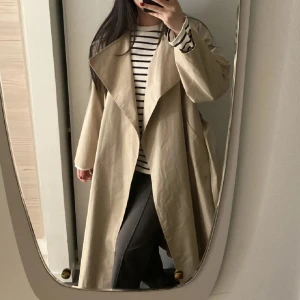 Beige trenchcoat från Mango - Säljer en oanvänd jättefin trenchcoat från Mango, med bred krage och bälte i midjan. Mycket fin passform och jättebra kvalité. Perfekt nu till våren🥰💛☀️Den är stor i storleken och passar mellan XS-M beroende på. 