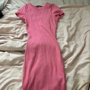 Rosa ribbad kortklänning - Säljer en rosa ribbad kortklänning. Klänningen har en figurnära passform.