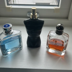 Tre herrparfymer från Nautica, Jean Paul Gaultier och Giorgio Armani - Säljer tre olika herrparfymer: Nautica Voyage med blått innehåll i en fyrkantig flaska, Jean Paul Gaultier Le Male i en svart kroppformad flaska och Armani Code med orange vätska i en elegant rundad flaska. Perfekt för dig som vill testa olika dofter.