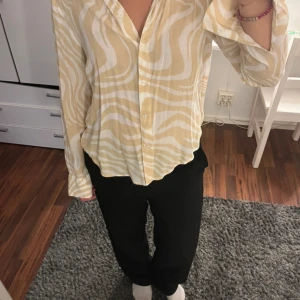 beige och vit mönstrad skjorta - • säljer en beige och vit skjorta med vågigt zebramönster. • skjortan har knappar framtill, lång ärm och en avslappnad passform. • perfekt för dig som gillar unika mönster och vill sticka ut lite extra. • size 32, men passar som en 36/34/38