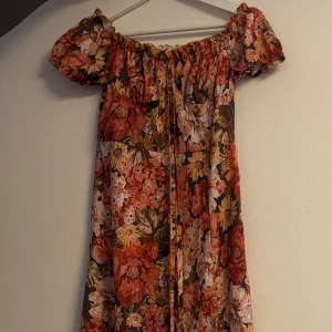 Blommig långklänning med puffärm och slits - Superfin långklänning med stora blommor i rött, orange, beige och grönt. Slits 