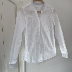 Vit skjorta med ljusblå detaljer - Vit skjorta med matchande detaljer vid krage och ärmslut. Enkel och stilren modell tillverkad av 100% bomull. Tyvärr skrynklig på bilden🫶