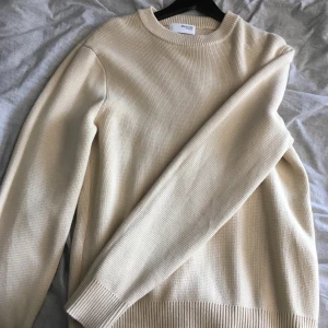 Beige stickad tröja från Selected Homme - Säljer en stilren beige stickad tröja från Selected Homme. Tröjan har rund halsringning, ribbade muddar och är långärmad. Perfekt för lager-på-lager och enkel att matcha med jeans eller chinos.