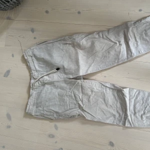 Beiga linnebyxor från Dressmann M - Snygga och luftiga beiga linnebyxor från Dressmann i storlek M. Byxorna har resår och snörning i midjan för skön passform. Perfekta för varma dagar när du vill ha en avslappnad och stilren look.