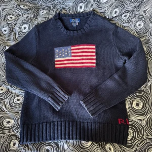 Polo Ralph lauren tröja  - Säljer en fin polo Ralph lauren stickad tröja iconic flag jumper i mycket bra skick. Den är bara lite solblekt vid kragen och ärmen men det märks inget stort. Går att köpa ny för runt 2100kr mitt pris 1199kr! Om några funderingar finns är det bara att skriva! St 14-16