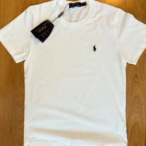 Vit Ralph Lauren T-shirt - !!!Gratis frakt om du köper idag!!! Säljer nu denna extremt snygga polo Ralph Lauren tishan för endast 400kr, pris kan diskuteras. Nyskick har testat att använda , ingen defekt alls kanske någon gång. Storlek S, perfekt för sommaren ☀️😍