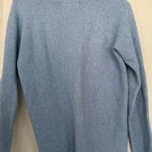 Ljusblå stickad tröja med rund hals - Mysig ljusblå stickad tröja med rund halsringning och långa ärmar. Tröjan har en enkel och klassisk design med ribbade muddar vid ärmslut och nederkant. Perfekt för lager-på-lager och chill dagar. Är lite noppig som du ser på bilden skriv om mer info eller om du är intresserad.