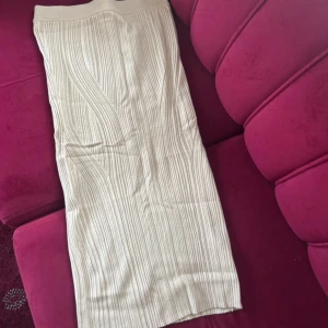 Beige ribbad långkjol - Snygg beige långkjol med ribbad struktur och hög midja. Kjolen har en rak passform och är perfekt för dig som gillar en stilren och enkel look. Passar till både sneakers och boots.