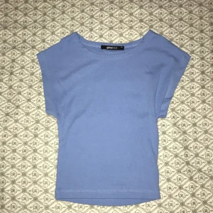 Ljusblå topp från Gina Tricot - Enkel och stilren ljusblå topp från Gina Tricot. Modellen har korta ärmar och rund halsringning. Perfekt att matcha med jeans eller kjol för en clean look. Mjuk och skön bomullskänsla.