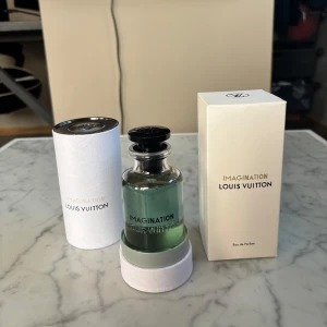 Louis Vuitton Imagination parfym - Lyxig parfym från Louis Vuitton, Imagination Eau de Parfum. Flaskan är i genomskinligt glas med svart rund kork och LV-logga på toppen. Parfymen har en ljusgrön nyans och kommer i elegant vit kartong och cylinderförpackning.