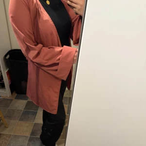 Rosa omlott kimono med bälte - Snygg rosa kimono med omlottmodell och knytbart bälte i midjan. Jackan har vida ärmar och en rak, lite längre passform. Perfekt för dig som vill ha en chill men ändå stilren look. Materialet känns är svalt och perfekt för sommaren!☀️.