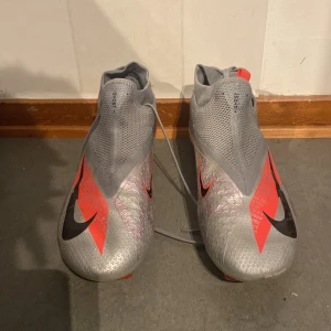Nike Phantom Vision grå/röda fotbollsskor - Nike Phantom Vision fotbollsskor i grått med röda och svarta detaljer. Storlek 42 1/2 och pris kan diskuteras.