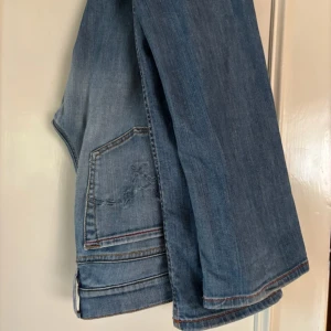 Diesel LIV ljusblå jeans med stretch - Säljer ett par ljusblå jeans från Diesel, modell LIV. Jeansen har klassisk femficksdesign, röda sömmar och broderad detalj på bakfickan. Materialet är stretchigt jeans för extra komfort. Perfekta för dig som gillar en avslappnad men snygg look.