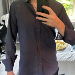 Mörkblå randig skjorta Hugo Boss  - Hej, Säljer en stilren mörkblå skjorta från Hugo Boss med tunna vita ränder. Skjortan är i slim fit-modell i storlek M, har långa ärmar och klassisk krage. Knappar framtill och diskret mönster ger en snygg touch. Hör av dig vid frågor eller funderingar!😁