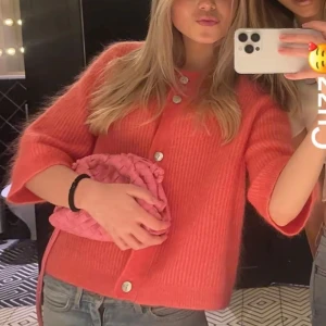 Rosa stickad kofta med knappar - Superfin rosa stickad kofta med stora vita knappar och trekvartsärmar. Koftan har en loose passform och är croppad i modellen, vilket gör den perfekt att slänga över en topp. Mjuk och mysig, passar både till jeans och kjol. Köpte för 2000kr använd typ 3 ggr❣️