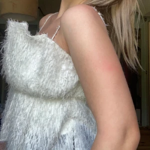 Vit fluffig kortklänning med tunna band - Supersöt vit kortklänning med tunna axelband och fluffig, texturerad yta som ger en unik look. Klänningen har en lös passform och är perfekt för dig som vill sticka ut med en cool och trendig stil. Perfekt för sommarens alla tillfällen!