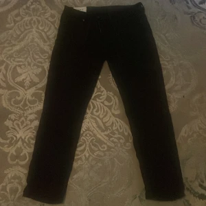 Svarta regular fit jeans från H&M - Svarta jeans från H&M i regular fit med klassisk femficksdesign och dragkedja. Byxorna har en rak passform och är tillverkade i ett mjukt bomullsmaterial med lite stretch. Perfekta för en clean och enkel stil.