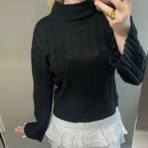 Svart ribbad polotröja från Boohoo - Svart ribbstickad polotröja från Boohoo med hög krage och långa ärmar. Tröjan har en loose fit och är perfekt för lager-på-lager. Mjuk och skön känsla, passar till allt och är enkel att styla.