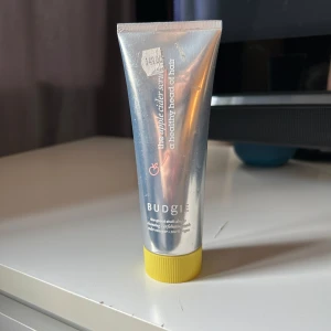 Budgie Schampo Scrub - Budgie the apple cider scrub i en silvrig tub med gul kork. Produkten är exfolierande och innehåller äppelcidervinäger, perfekt för att rengöra och fräscha upp hårbotten. Tuben är smidig och lätt att använda. Använd 1 gång testad 