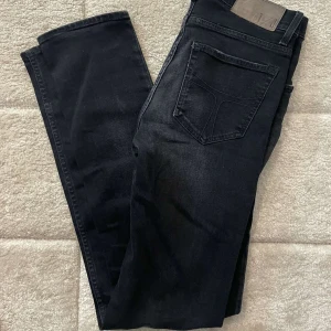 Tiger of sweden jeans  - Snygga svarta jeansbyxor med klassisk femficksdesign och raka ben. Jeansen har en mörk tvätt och är tillverkade i ett mjukt denimtyg som sitter skönt hela dagen. Perfekta för dig som gillar en stilren och enkel look.