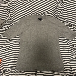 Grå och orange tröja från Lindex och Kappahl  - Två stilrena tröjor från Lindex och Kappahl , en i grått och en i orange. Båda har rund halsringning och halvlånga ärmar. Perfekta för lager-på-lager och funkar året runt. Materialet känns mjukt och lätt, troligen bomull eller en bomullsblandning.