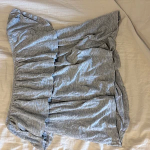 Grå offshoulder volangtopp - Superfin grå offshoulder topp med volanger och lös passform. Perfekt för dig som gillar en avslappnad men ändå trendig stil. Mjuk och skön i bomullsmaterial, lätt att matcha med både jeans och kjol.