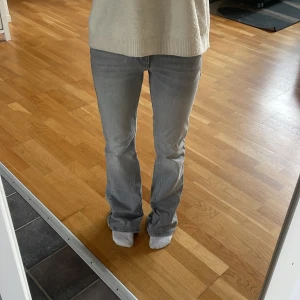 Grå bootcut jeans med låg midja - Snygga grå jeans med bootcut och låg midja. Jeansen har klassisk femficksdesign, dragkedja och knapp framtill. Materialet är mjukt denim som sitter skönt och följer kroppen. Perfekta för dig som gillar en avslappnad men trendig look. Pris kan diskuteras, skriv för fler bilder!!