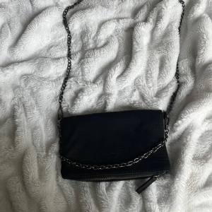 Svart axelväska med kedja - Snygg svart axelväska med kedjedetaljer och dragkedja. Skriv för fler bilder. Pris kan diskuteras,