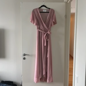 Rosa Balklänning  - Säljer en otroligt vacker rosa omlottklänning från Sisters Point. Klänningen har knytband i midjan som ger en justerbar passform passform. Perfekt för studentbal, 9:ans bal eller bara en härlig sommarklänning❤️använd endast en gång