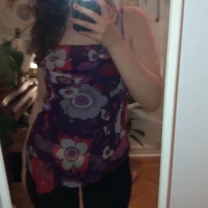 Blommig linne i lila och rosa - Säljer ett snyggt linne med blommigt mönster i lila, rosa och vitt. Linnet har smala axelband och en lite lös passform som ger en bekväm känsla. Perfekt för sommarens varma dagar!