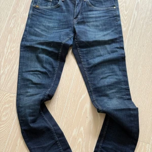 Mörkblå jeansbyxor Tiger of Sweden  - Snygga mörkblå jeansbyxor från Tiger of Sweden i slim fit. Byxorna har en klassisk femficksdesign och är tillverkade i ett slitstarkt denimtyg. Perfekta för en stilren look.