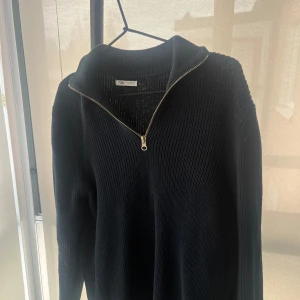 Marine blå ribbad tröja från Zara - Säljer en stilren mörkblå half zip från Zara med dragkedja vid halsen. Perfekt för en avslappnad men ändå snygg look. Tröjan har långa ärmar och en bekväm passform.