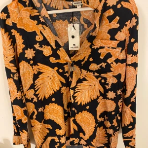 Mönstrad pyjamas set - Säljer en super skön och sval set från Indiska i svart och orange. Använts en gång, perfekt nu på sommaren när värmen kommer.