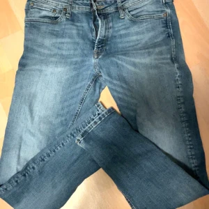 Jeans från Jack&jones - Säljer ett par klassiska blå jeansbyxor med en normal passform. De har en traditionell femficksdesign och en knappgylf. Perfekta för en avslappnad stil.