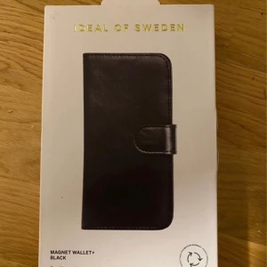 Svart Magnet Wallet+ från iDeal of Sweden - Säljer en stilren svart Magnet Wallet+ från iDeal of Sweden, designad för iPhone 12/12 Pro. Plånboken har en magnetisk stängning och är perfekt för att hålla din telefon och kort på plats. En praktisk och elegant accessoar för din mobil.