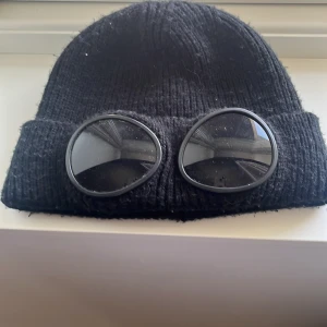 Svart stickad mössa med glasögondetalj - Svart c.p company mössa