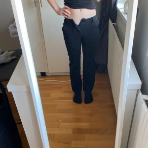 Svarta byxor med dragsko - Snygga svarta byxor med dragsko i midjan. De har en rak passform och är perfekta för en avslappnad stil. Byxorna är tillverkade i ett mjukt material som ger en bekväm känsla hela dagen.