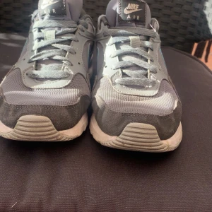 Nike Air sneakers i grått och blått - Snygga Nike Air sneakers i grått med blå detaljer. Skorna har en klassisk design med snörning och en bekväm sula. Perfekta för en avslappnad stil.