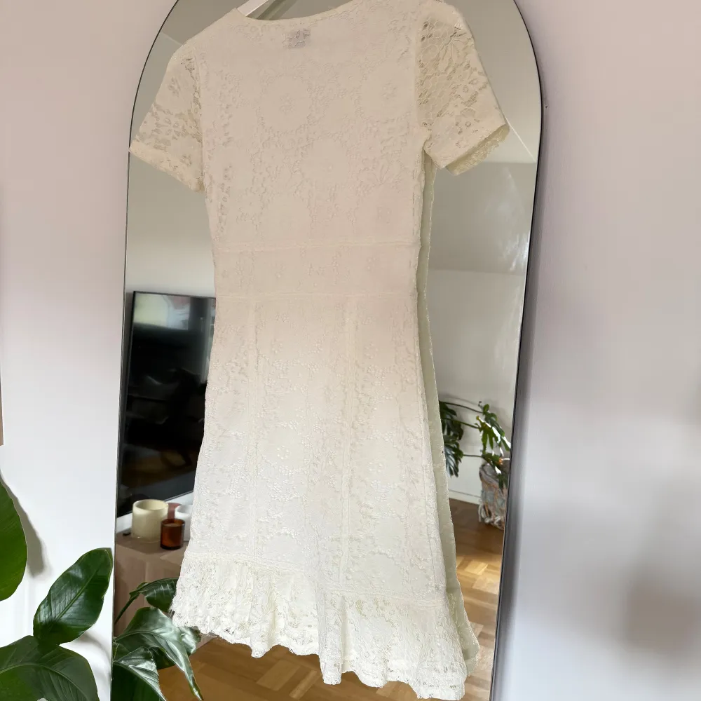 Vit klänning i spets från bubbleroom. Klänningen har en volangdetalj nedtill. Använd 1 gång när jag tog studenten. Är 165cm . Mekot.