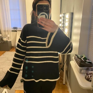 Svart och vit randig tröja - Säljer en svart tröja med vita ränder. Tröjan har långa ärmar och en avslappnad passform. Perfekt för en stilren och bekväm look.