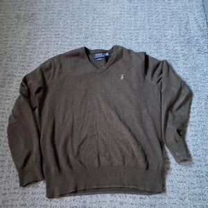 Brun stickad tröja Polo Ralph Lauren - Säljer en stilren brun v-ringad tröja från Polo Ralph Lauren. Tröjan är tillverkad i mjuk pima bomull och har långa ärmar. Perfekt för en klassisk och avslappnad look. Storlek s