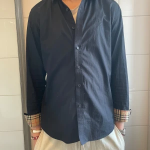Burberry skjorta  - En tvär fet skjorta från lyx varumärket Burbberry. Köpt för 4299 för något år sen. Storlek Medium herr. Model, 187 och väger 70 cirka, men sitter lite litet på modellen. Extremt bra skick. Mitt pris 799, bara att skriva ifall ni har frågor! Priset är inte helt fast. 