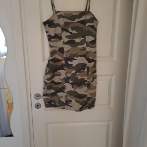 Camouflage klänning från H&M - Snygg camouflage klänning från H&M med smala axelband och dragkedja bak. Perfekt för en cool och avslappnad stil. Klänningen har en tight passform och är i ett mjukt material.