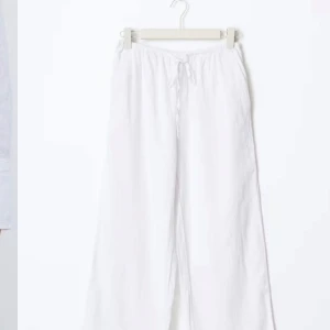 Vita linnebyxor med snörning - Säljer ett par vita linnebyxor med snörning i midjan. Byxorna har en avslappnad passform och är perfekta för varma sommardagar. De är tillverkade i ett lätt och luftigt material som ger en skön känsla. Nyskick Stl 146-152 men passar xs stora i storleken